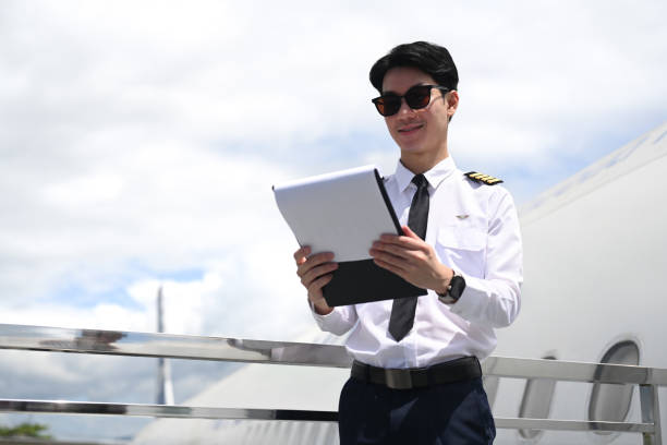 istock Pilot wearing sunglasses reading paper while standing beside an airplane with cloudy sky on background 2166841228