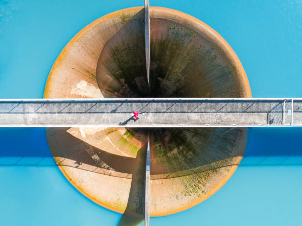 istock Bridge to power, man walking on bridge over circular water overflow. 2166841438