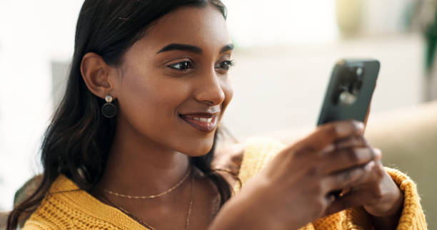 istock Indian woman, connection and smartphone in home for scroll, typing and text message on sofa in lounge. Girl, network and mobile app for creating profile, chat and choice for match on dating website 2166841990