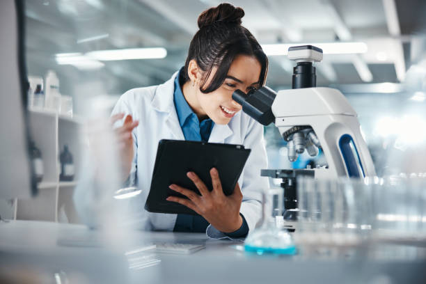 istock Woman, scientist and microscope with tablet in lab for experiment research, medical data and science information. Smile, researcher and digital for biotechnology study, feedback and vaccine solution 2166845329