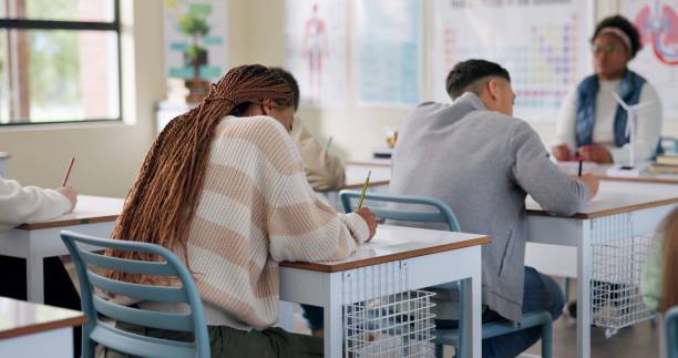 istock Back, education or class in high school for test, lesson or biology assessment. Questionnaire, writing or students at desk for quiz, learning evaluation or concentration for knowledge and development 2166845686