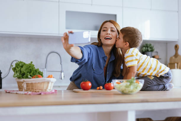 istock Son kissing mother during kitchen selfie session 2166846950