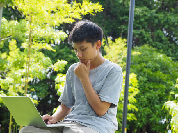 istock A man is making a contemplative gesture while looking at a laptop in an outdoor park. 2166847864