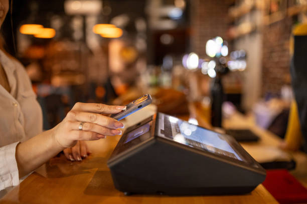 istock Woman using her phone to pay for coffee in a pub 2166863284