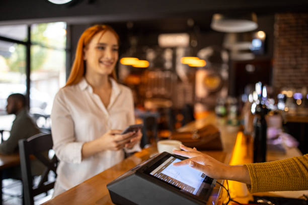 istock Woman using her phone to pay for coffee in a pub 2166863303