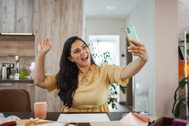 istock Woman takes a selfie while sitting at a table in a bright room 2166865865