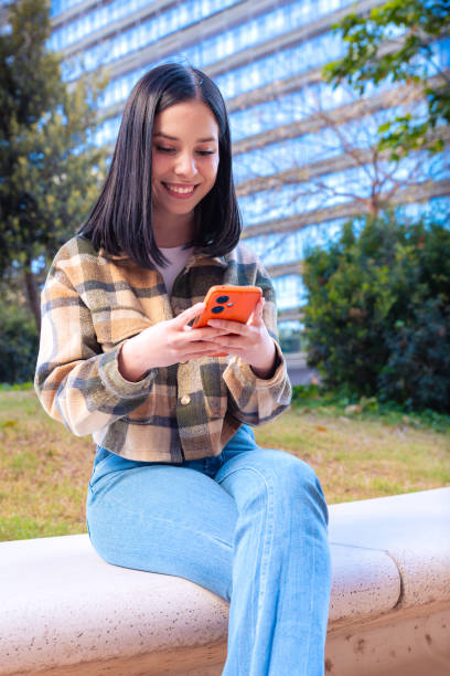 istock Vertical portrait smiling young female using smartphone app outdoors. 2166869654