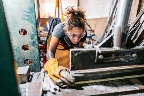 Young Woman Bending Metal On Machine In A Workshop