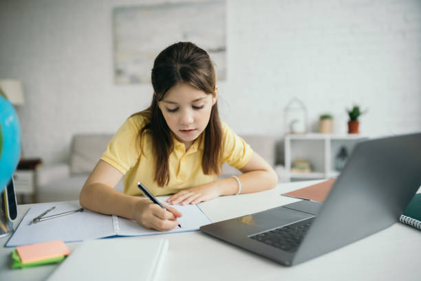 istock Little girl studying at home with laptop and notes during remote learning 2166870667