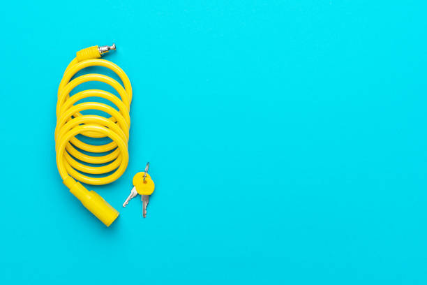 Yellow bike lock with keys over turquoise blue background. Top down flat lay photo of bicycle lock with copy space.