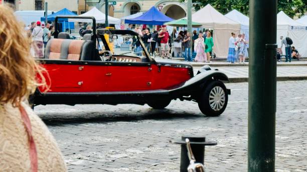Prague, Czech Republic - 8/8/2024, Red long luxury tourist sightseeing car nearby the Charles bridge.