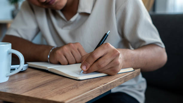 istock Young teenager's hand writing in notebook at home 2166882969
