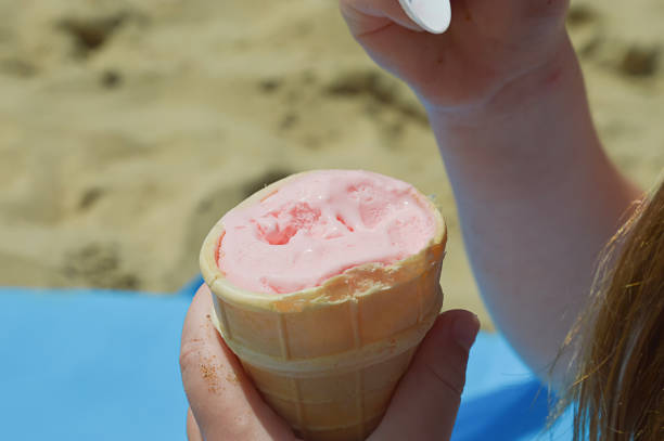 istock a child eats ice cream in a waffle cup on the beach. summer vacation, cold dessert. background for the design. 2166884646