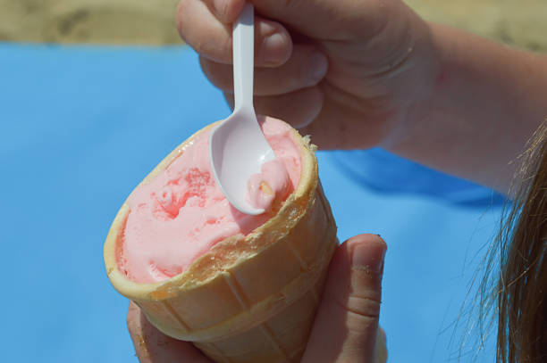 istock a child eats ice cream in a waffle cup on the beach. summer vacation, cold dessert. background for the design. 2166884649