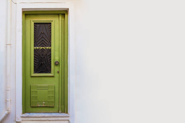 The colorful pastel facade and forest green front door of a traditional terraced London mews townhouse.