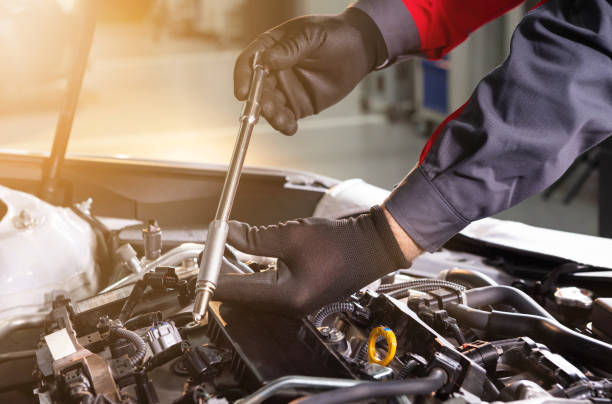 mechanic makes diagnostics of the car in the engine. car service and audit by an employee in a large car service. candle replacement. black mittens and car tool mechanic makes diagnostics of the car in the engine. car service and audit by an employee in a large car service. candle replacement. black mittens and car tool chrome man stock pictures, royalty-free photos & images