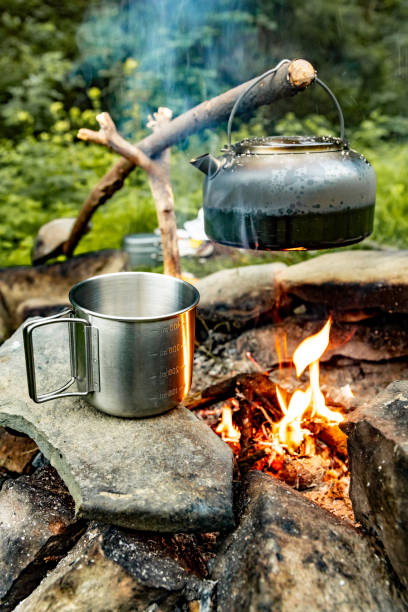 istock Making tea over an open fire in the forest. The kettle is hanging on a stick on the fire. 2166892240