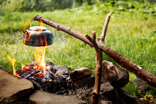istock Making tea over an open fire in the forest. The kettle is hanging on a stick on the fire. 2166892314