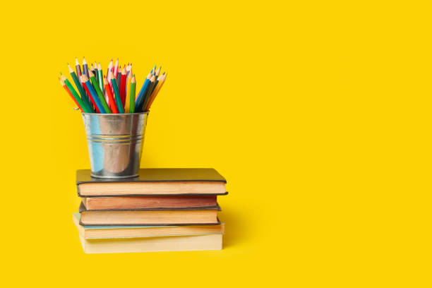 istock A bucket with colored pencils over books on a yellow background with copy space 2166898702