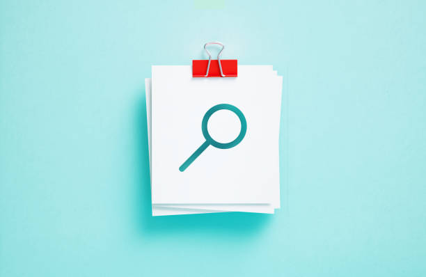 Cutout magnifier symbol on post it notes on blue background. Horizontal composition. Search concept.