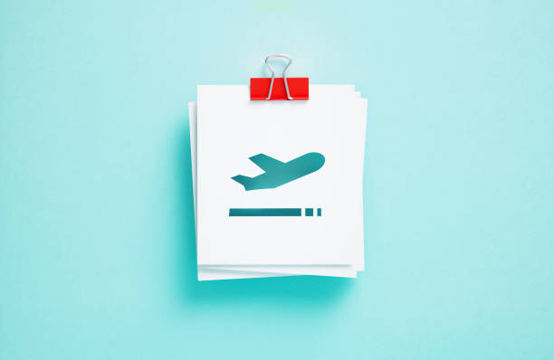 Cutout airplane symbol on post it notes on blue background. Horizontal composition. Departures concept.