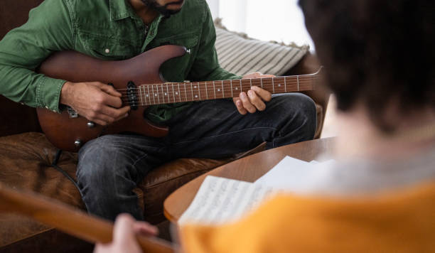 istock Young Guitar Instructor Gives Private Lesson To Male Student 2166900002