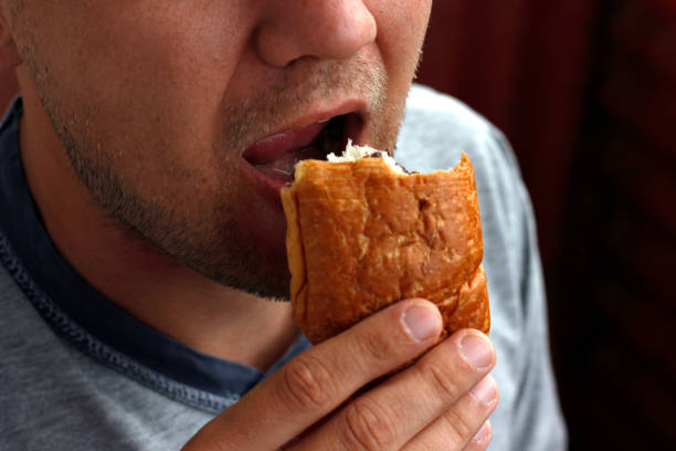 a man eats a bun, a man's mouth bites a bun close-up, nutrition concept