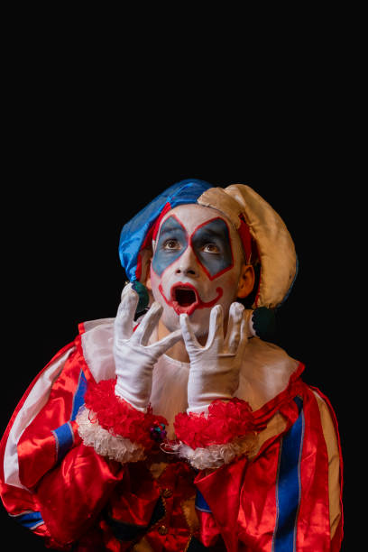 istock suprised clown looking up on black background 2166905618