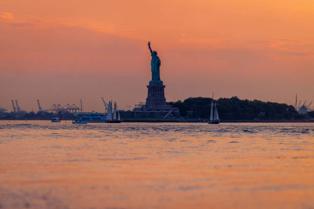 The sun sets behind the Statue of Liberty