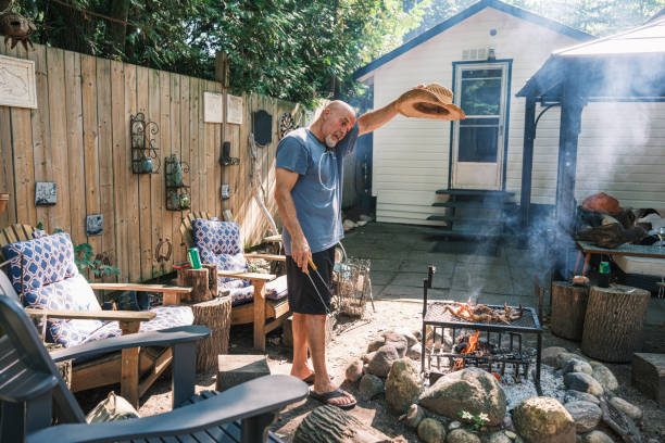 istock Mature man roasting chicken wings on outdoor fire pit BBQ 2166910425