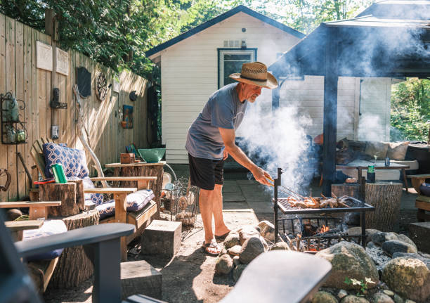 istock Mature man roasting chicken wings on outdoor fire pit BBQ 2166910444