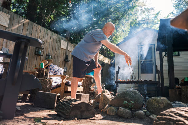 istock Mature man roasting chicken wings on outdoor fire pit BBQ 2166910451