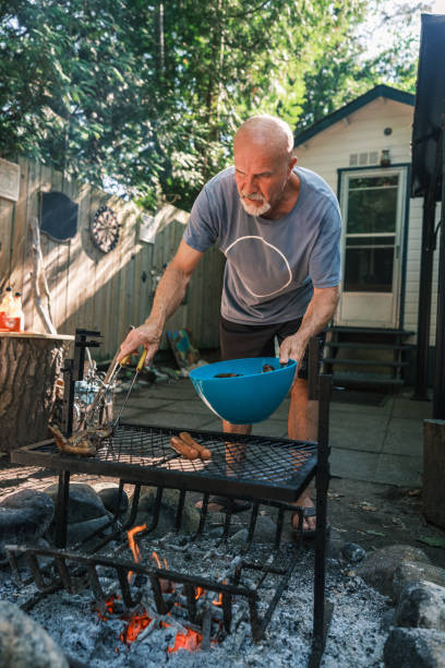 istock Mature man roasting chicken wings on outdoor fire pit BBQ 2166910464