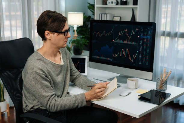 istock Trader in casual day taking note in stock exchange market graph. Pecuniary. 2166911025