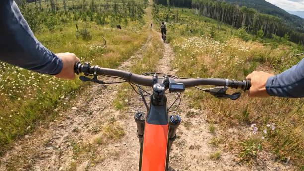istock POV past handlebars to mountain bikers on trail 2166915289