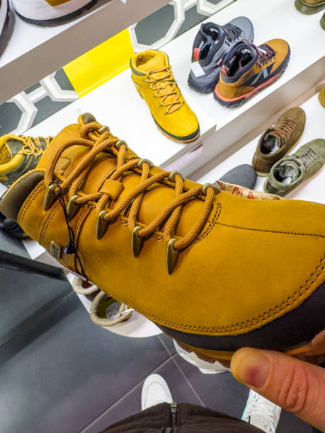 striking pair of mustard yellow hiking boots, prominently displayed in a shoe store. The boots feature robust laces, a sturdy design, and a modern aesthetic, appealing to adventurous spirits and trendsetters alike. In the background, various other styles of footwear hint at the diverse selection available for shoppers seeking the perfect blend of fashion and function.