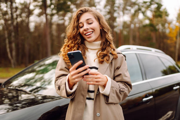 istock Young woman standing by the car and using phone. 2166924899