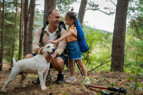 Father and daughter playing with a dog in a forest