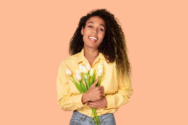 istock Smiling black woman poses with white tulips bouquet 2166926310