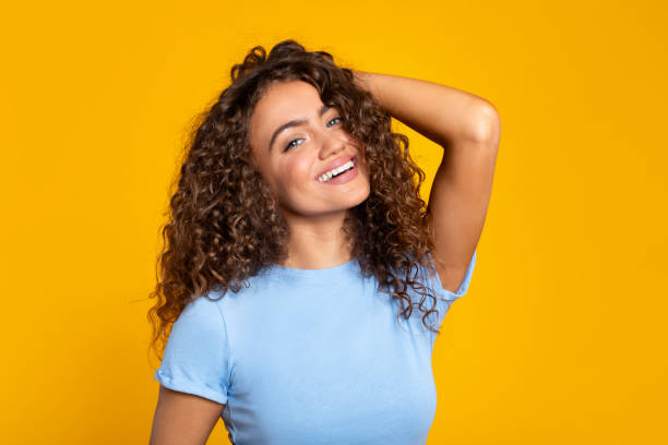 istock Delighted young woman smiling brightly on yellow 2166926364