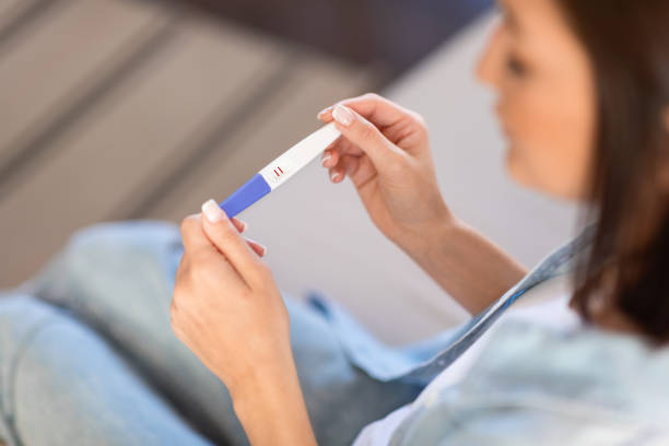 istock unrecognizable young lady looking at positive pregnancy test at home 2166927111