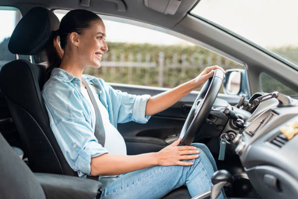 istock Smiling expectant lady happily drives her car, side view shot 2166927124