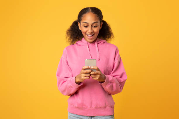 istock Black girl scrolling social media on smartphone over yellow backdrop 2166927366