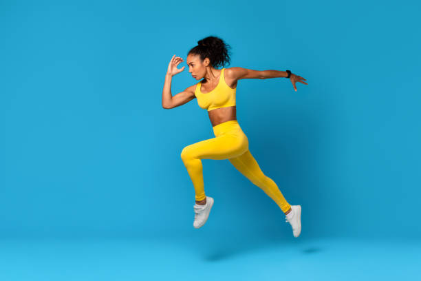 istock African Lady In Fitwear Exercising Jumping Over Blue Studio Background 2166927499