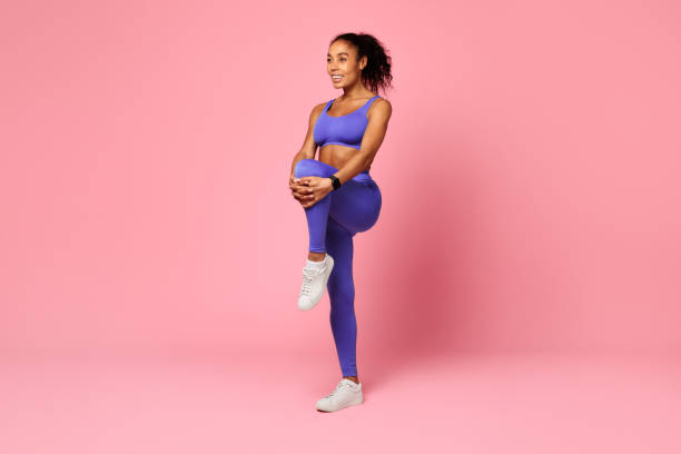 istock african lady stretching leg muscles holding knee to chest, studio 2166927507