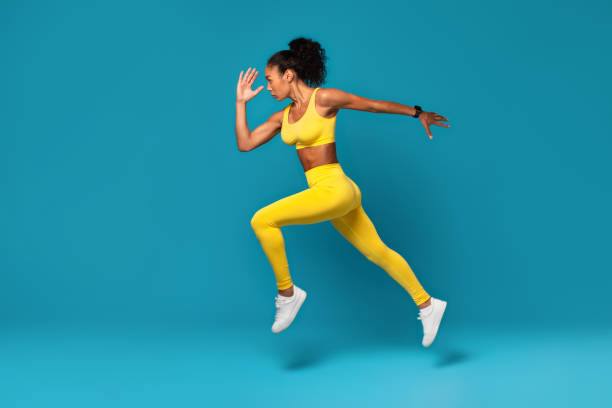 istock Athletic black woman leaping during dynamic workout on blue backdrop 2166927509