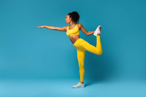istock Fit African Lady Stretching Raised Leg Extending Arm, Blue Background 2166927541