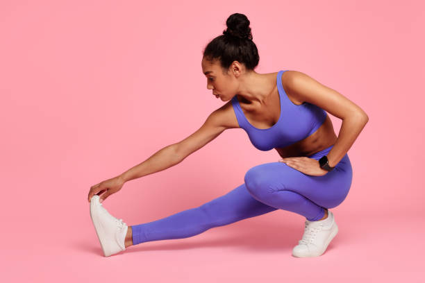 istock Sporty young black lady engages in stretching exercises, pink backdrop 2166927593