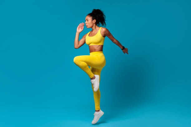istock African American sportswoman doing elbow to knee standing pose, studio 2166927603