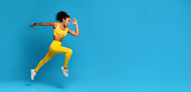 istock Dynamic athlete black woman in mid-jump on blue background 2166927624